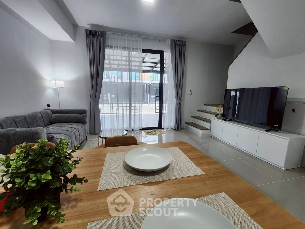 Modern living room with stylish decor and natural light, featuring a cozy sofa and sleek TV setup.