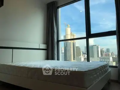Spacious bedroom with large window offering stunning city skyline view, perfect for urban living.