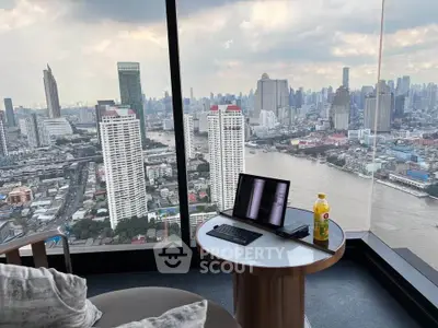 Stunning high-rise city view from a modern apartment with floor-to-ceiling windows and cozy seating area.