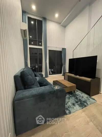 Modern living room with high ceilings, large windows, and stylish furniture in a contemporary apartment.