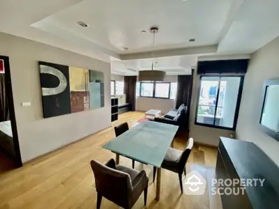 Modern living room with hardwood floors and city view, featuring stylish furniture and contemporary art.