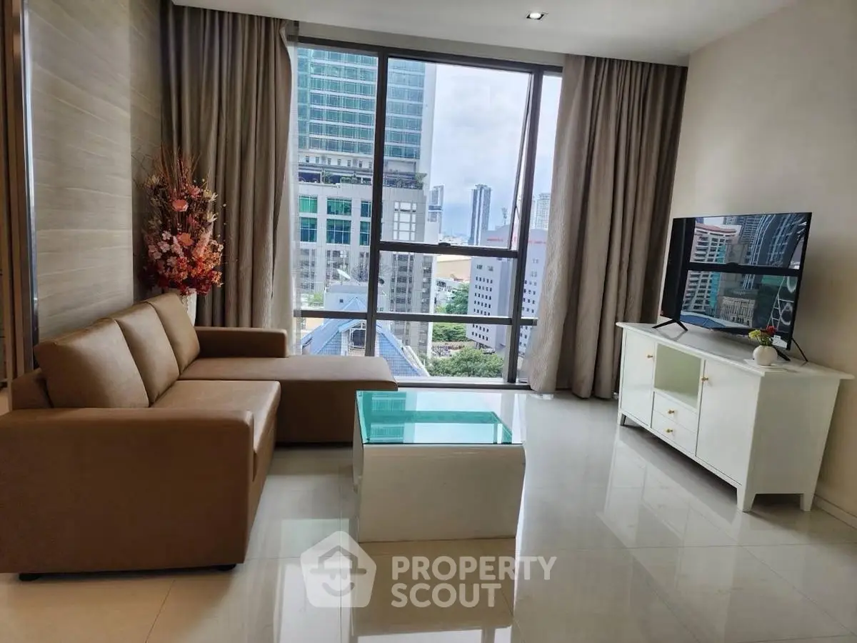 Modern living room with city view, featuring sleek furniture and large windows for natural light.