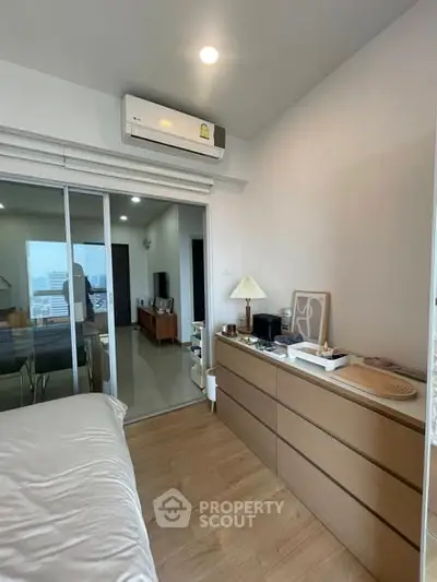 Modern bedroom with sleek wooden dresser and sliding glass doors leading to a living area.