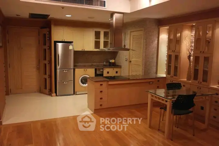 Spacious kitchen with modern appliances and wooden cabinetry in a cozy apartment setting.
