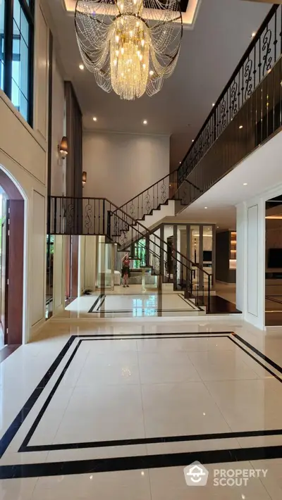 Luxurious grand entrance with elegant chandelier and modern staircase in upscale property