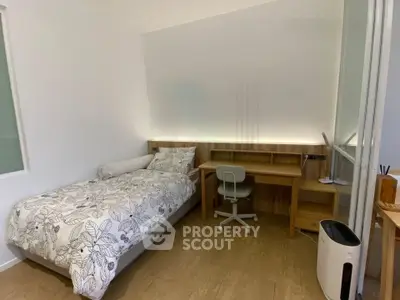 Modern bedroom with study area featuring sleek desk and comfortable bed, perfect for students or professionals.