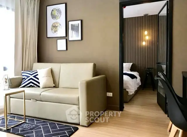 Modern living room with beige sofa and stylish decor leading to a cozy bedroom.