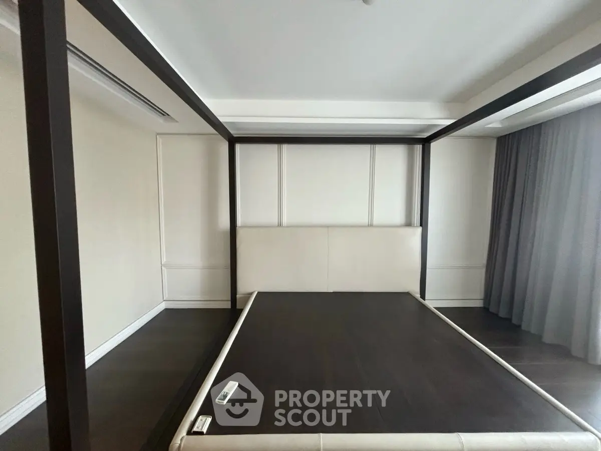 Spacious bedroom with modern four-poster bed frame and elegant curtains.