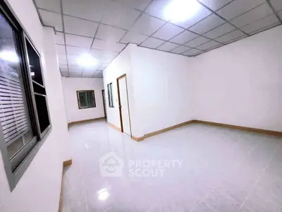 Spacious empty room with tiled flooring and bright lighting, ideal for customization.