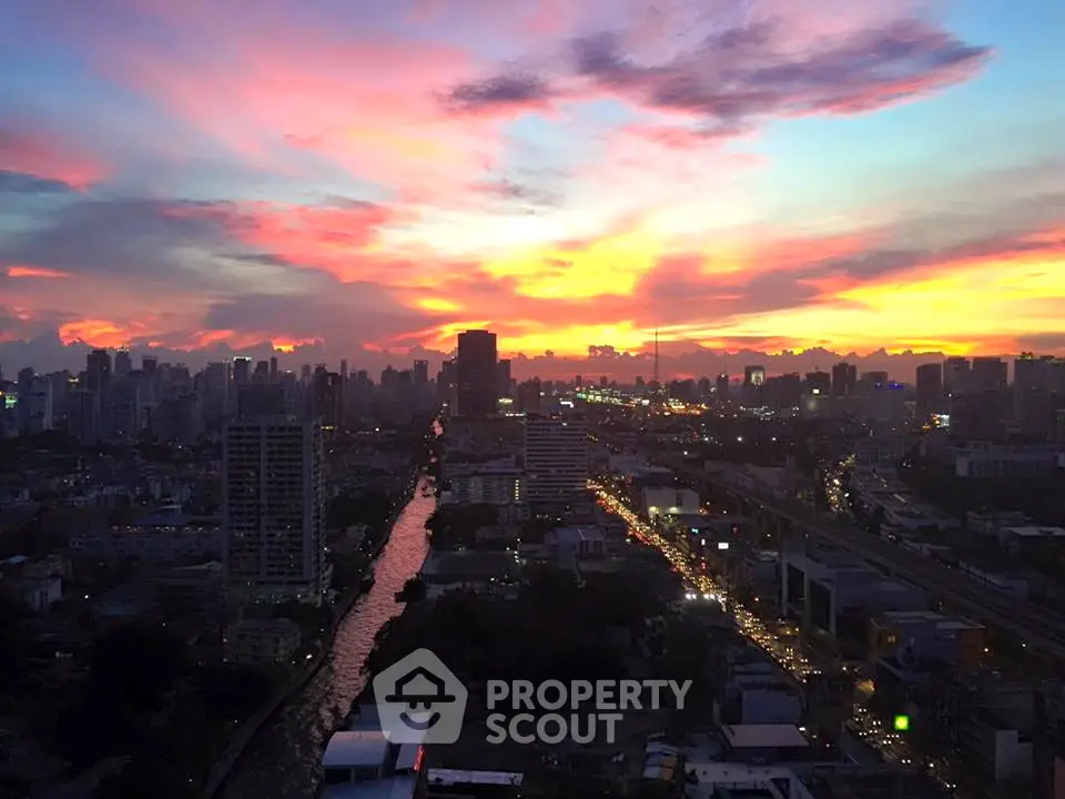 Stunning cityscape view at sunset with vibrant sky over urban skyline and river.