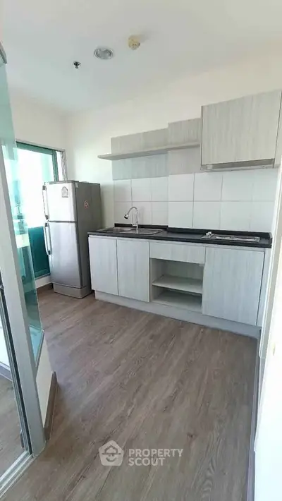 Modern kitchen with sleek cabinetry and stainless steel fridge in a bright apartment.
