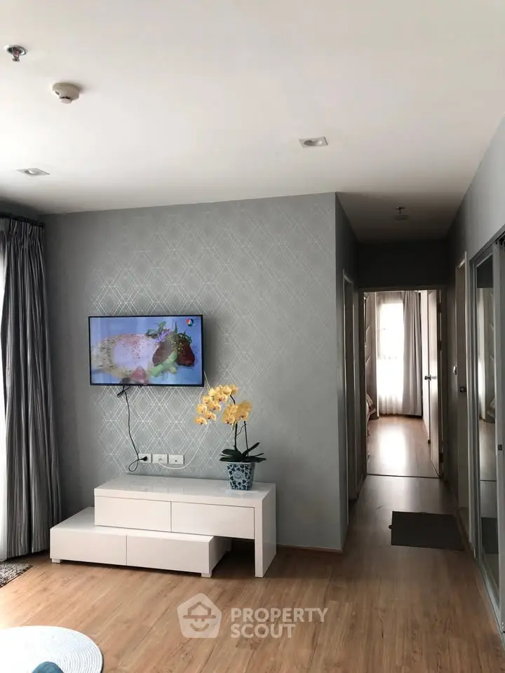 Modern living room with stylish decor and wall-mounted TV, featuring elegant wooden flooring and natural light.