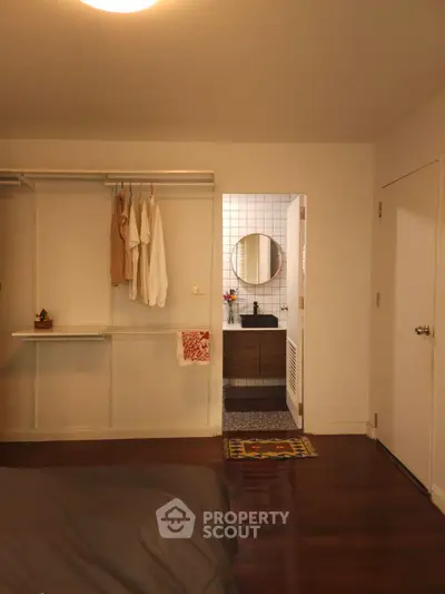 Cozy bedroom with open closet and view into modern bathroom