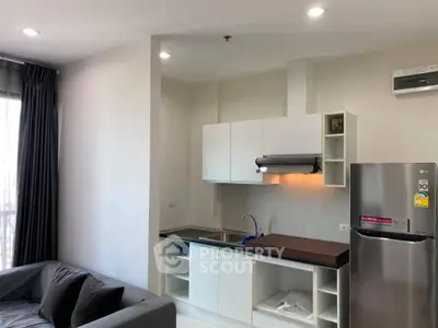 Modern kitchen with sleek cabinetry and stainless steel appliances in a cozy apartment setting.