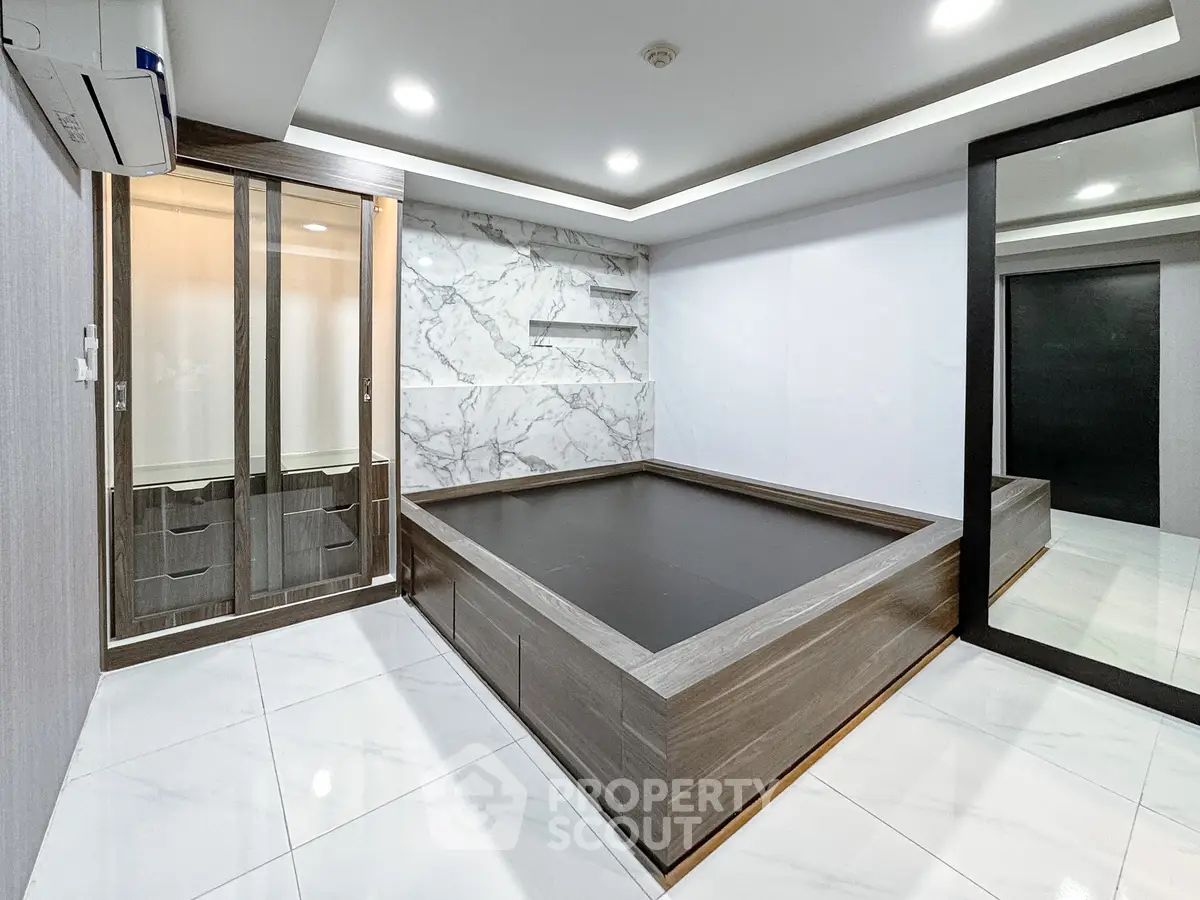 Modern bedroom with marble accent wall and built-in storage, featuring sleek design and spacious layout.