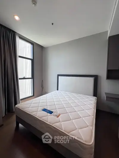 Modern bedroom with large window and minimalist design, featuring a comfortable mattress and sleek furnishings.