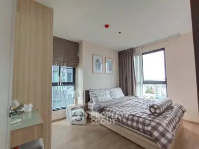 Cozy bedroom with modern decor and large windows offering natural light and city views.
