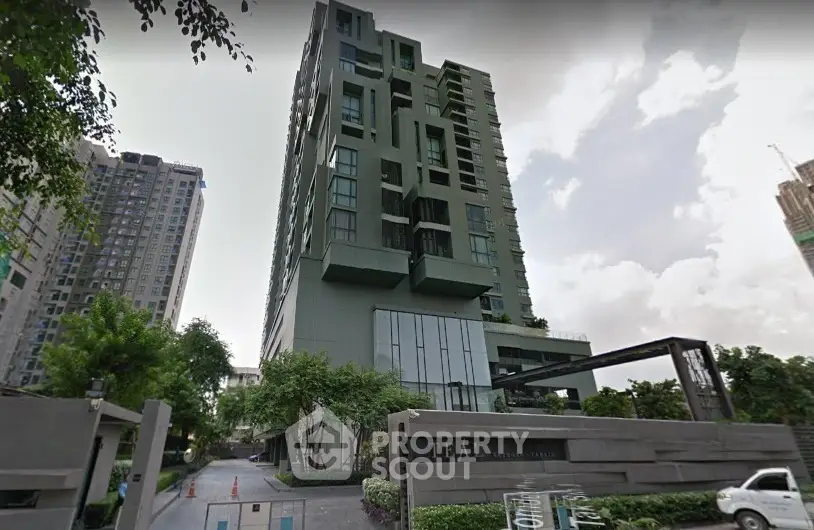 Modern high-rise building with lush greenery and sleek architectural design.