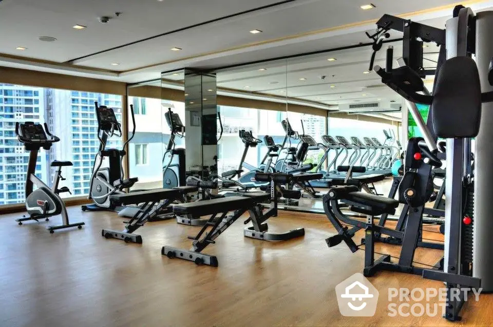 Modern gym with state-of-the-art equipment and city view in luxury apartment complex.