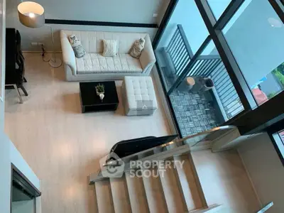 Modern living room with high ceiling and balcony view, featuring elegant furniture and natural light.