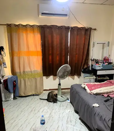 Cozy bedroom with air conditioning, fan, and stylish curtains, perfect for comfortable living.