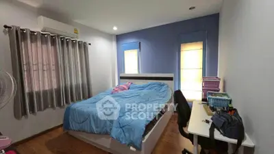 Cozy bedroom with blue accents and workspace, ideal for relaxation and productivity.