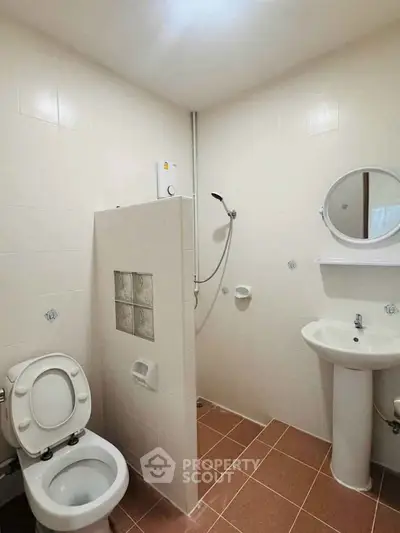 Compact bathroom with shower, toilet, and sink in a minimalist design.