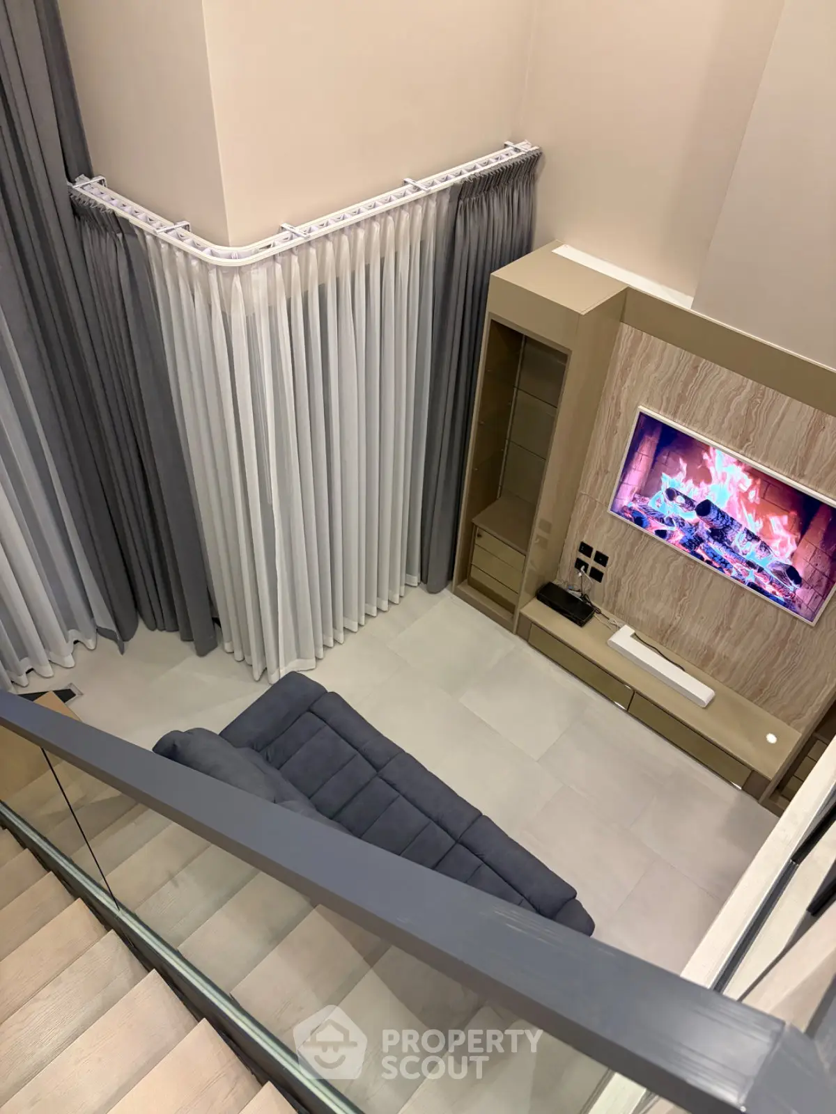 Modern living room with stylish decor and fireplace TV, featuring elegant curtains and sleek furniture.