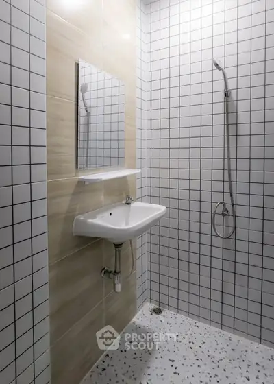 Modern minimalist bathroom with sleek white tiles and compact sink design.