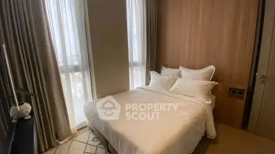 Cozy bedroom with modern decor and large windows offering natural light.