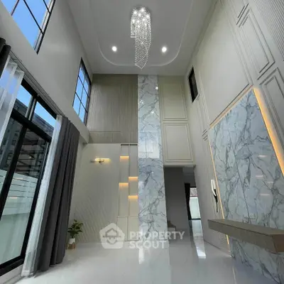 Luxurious high-ceiling living room with elegant marble accents and modern chandelier