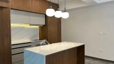 Modern kitchen with marble island and stylish pendant lights in a contemporary apartment.