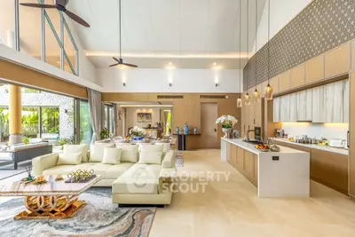 Luxurious open-plan living room with high ceilings and modern kitchen in a tropical villa.