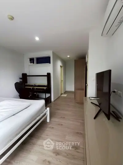 Modern bedroom with study area and sleek design, featuring a TV and air conditioning.