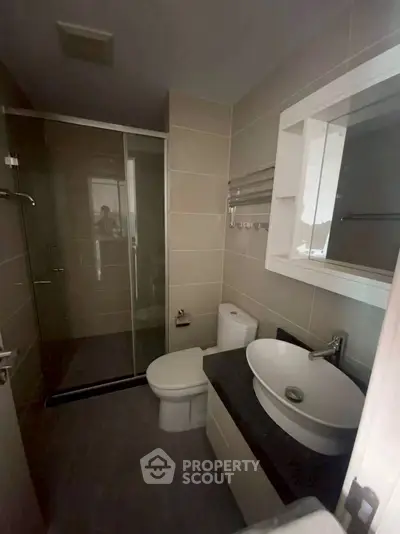 Modern bathroom with glass shower and stylish sink in real estate property