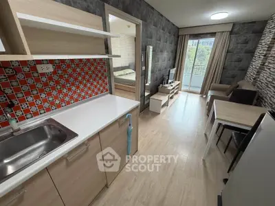 Modern studio apartment with open kitchen and cozy living area, featuring stylish decor and a balcony view.