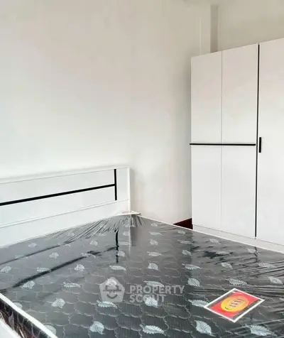 Modern bedroom with sleek white wardrobe and new mattress in a bright space.