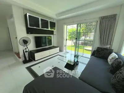 Spacious living room with modern furniture and garden view through sliding glass doors.