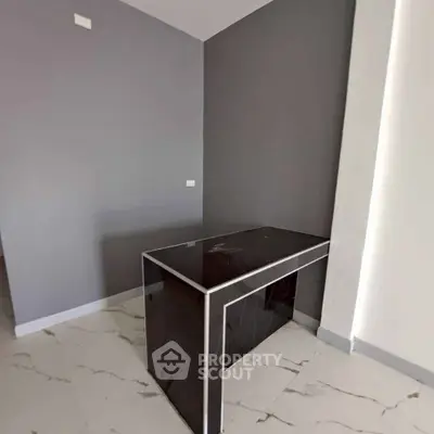 Modern minimalist interior with sleek black table and gray walls, perfect for a stylish home office or study area.
