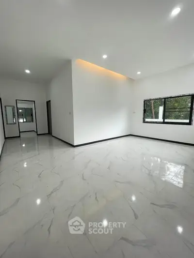 Spacious modern living room with large windows and elegant marble flooring.