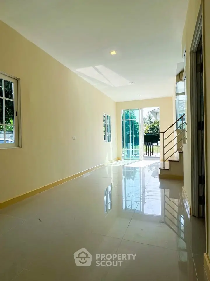 Spacious sunlit living room with glossy floors and garden view, perfect for modern living.