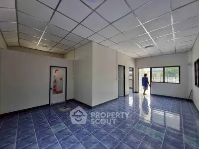 Spacious tiled room with large windows and decorative door, ideal for versatile use.