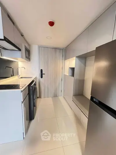Modern compact kitchen with sleek cabinetry and integrated appliances in a stylish apartment.