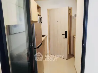 Modern compact kitchen with stainless steel fridge and sleek cabinetry