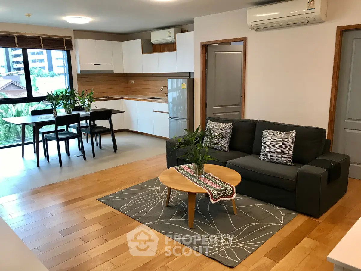 Modern open-plan living room with kitchen, featuring stylish decor and natural light.