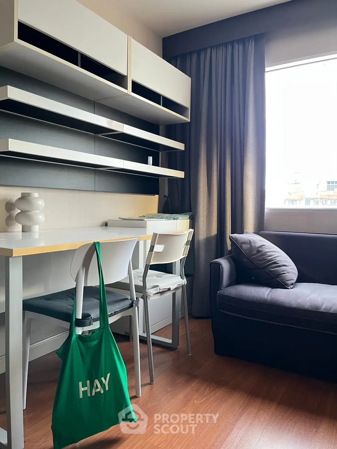 Modern study room with sleek shelving, cozy seating, and natural light from large window.