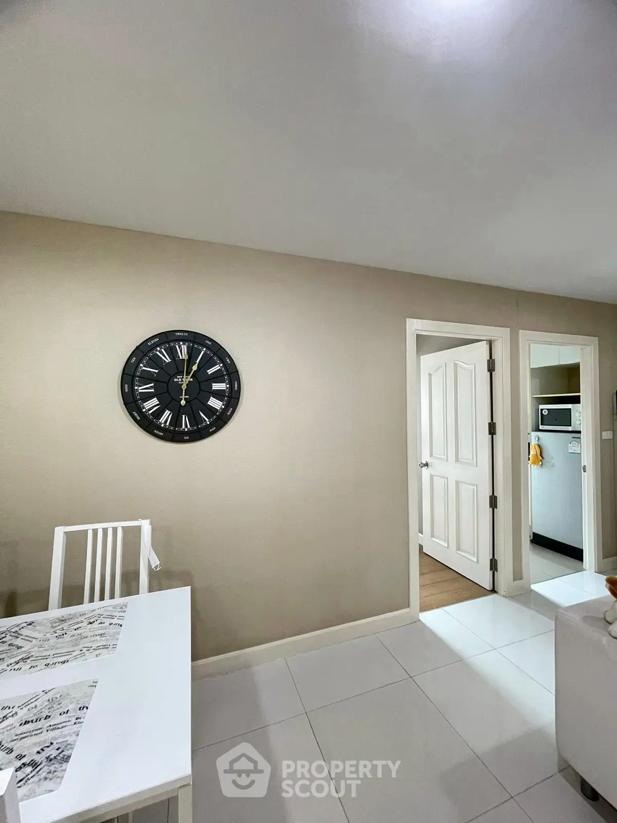 Modern dining area with wall clock and view into kitchen