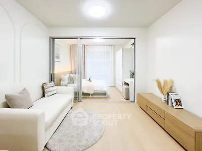 Modern open-plan living room with cozy bedroom, stylish decor, and natural light.