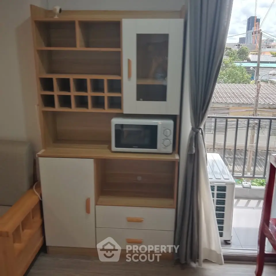 Modern living room with stylish storage unit and microwave, overlooking a balcony with city view.