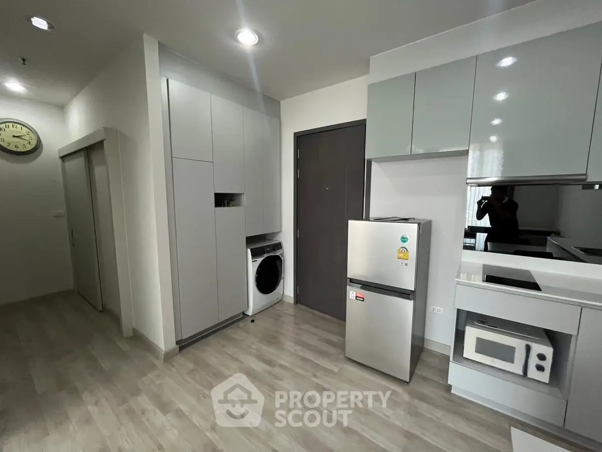 Modern kitchen with sleek appliances and washer in compact layout